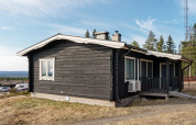 Zwarte houten lodge met wit dak in Kopparberg, Zweden, nabij bos en glooiend landschap gelegen.