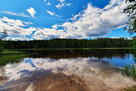 Lac paisible reflétant le ciel et la forêt près d'un gîte à Kopparberg, en Suède, sous de beaux nuages.