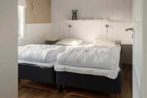 Chambre lumineuse avec deux lits simples et décoration sobre dans une maison de vacances à Kopparberg, Suède.