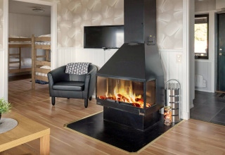 Salon d’une maison de vacances à Kopparberg, Suède, avec cheminée, fauteuil, TV et lits superposés.