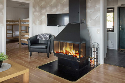 Woonkamer in een vakantiehuis in Kopparberg, Zweden met open haard, fauteuil, tv en stapelbedden.