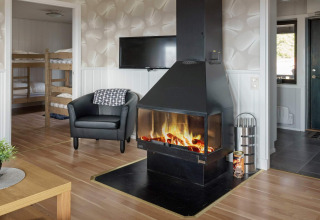 Woonkamer in een vakantiehuis in Kopparberg, Zweden met open haard, fauteuil, tv en stapelbedden.