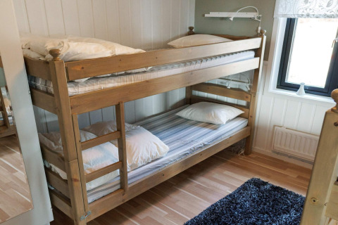 Houten stapelbed met wit beddengoed in een knusse kamer van een vakantiehuis in Kopparberg, Zweden.