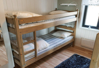 Houten stapelbed met wit beddengoed in een knusse kamer van een vakantiehuis in Kopparberg, Zweden.