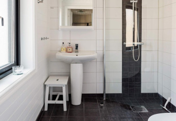 Salle de bain moderne dans une maison de vacances à Kopparberg, Suède, avec douche et lavabo.