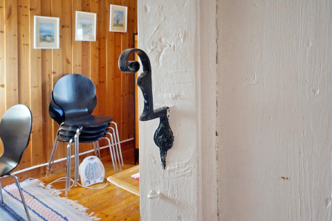 Interno di uno chalet vacanze a Vaxholm, Svezia, con pareti in legno, sedie nere e quadri appesi alle pareti.