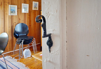 Innenansicht eines Chalets in Vaxholm, Schweden, mit Holzwänden, schwarzen Stühlen und Wandbildern.