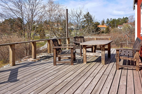 Terrazza in legno con mobili rustici all'aperto presso uno chalet a Vaxholm, Svezia, circondata dalla natura.