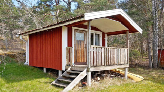 Cabaña roja de madera con porche en VAXHOLM, Suecia, alojamiento vacacional para 6 personas en el bosque.