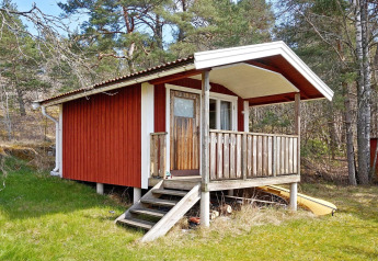 Rood houten chalet met een veranda in VAXHOLM, Zweden, vakantieverblijf voor 6 personen in het bos.