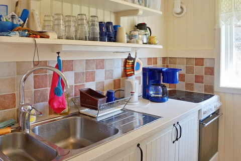 Cucina luminosa in una casa vacanze a Vaxholm, Svezia, con lavello, macchina da caffè e piastrelle colorate.