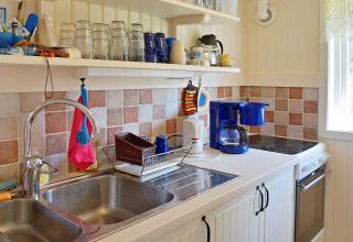 Cucina luminosa in una casa vacanze a Vaxholm, Svezia, con lavello, macchina da caffè e piastrelle colorate.