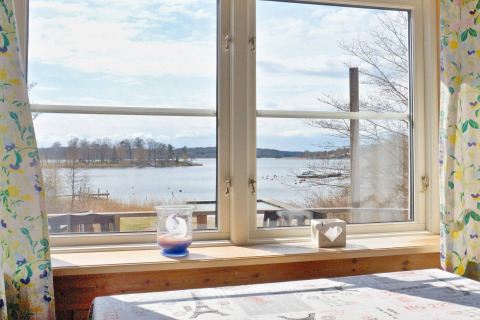 Vista da una finestra della casa vacanze per 6 persone a VAXHOLM, Svezia, sul lago e natura circostante.