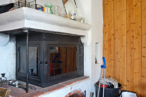 Camino con sportelli in vetro e accessori per la pulizia in una casa vacanze a Vaxholm, Svezia.