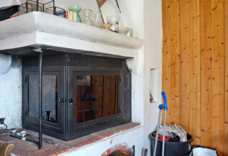 Camino con sportelli in vetro e accessori per la pulizia in una casa vacanze a Vaxholm, Svezia.