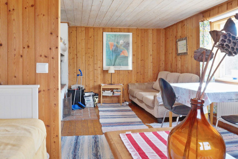 Soggiorno accogliente in uno chalet svedese a Vaxholm con pareti in legno, divano e luce naturale.