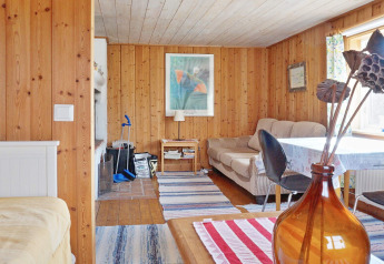 Cozy living room in a Swedish holiday chalet in Vaxholm with wood panels, sofa, and bright window light.