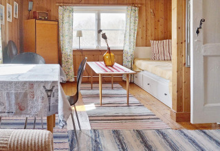 Accogliente zona giorno di una casa vacanze a Vaxholm, Svezia, con pannelli in legno e luce naturale.