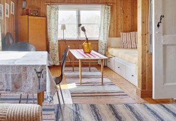 Salon chaleureux d'une maison de vacances à Vaxholm, Suède, avec boiseries et espace salle à manger lumineux.