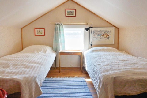 Camera da letto con due letti singoli e soffitto inclinato in uno chalet vacanze a Vaxholm, Svezia.