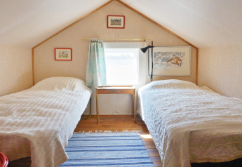 Chambre avec deux lits simples et plafond en pente dans un chalet de vacances à Vaxholm, Suède.