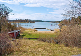Vue sur le lac et la plage depuis un chalet de vacances pour 6 personnes à Vaxholm, Suède, avec embarcadère.
