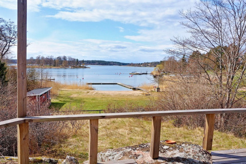 Vista da uno chalet a Vaxholm, Svezia, con terrazza in legno, pontile e paesaggio naturale del lago.