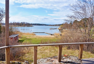 Vista da uno chalet a Vaxholm, Svezia, con terrazza in legno, pontile e paesaggio naturale del lago.