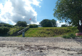Trap naar grasveld met Deense vlag bij vakantiehuis in Børkop, Denemarken, onder gedeeltelijk bewolkte lucht.
