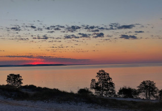 Zonsondergang boven zee met bomen en wolken, gezien vanaf het 6-persoons vakantiehuis in Børkop, Denemarken.