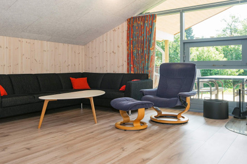 Woonkamer met zwarte hoekbank, fauteuil en raam in het 6-persoons vakantiehuis in Børkop, Denemarken.