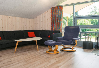 Woonkamer met zwarte hoekbank, fauteuil en raam in het 6-persoons vakantiehuis in Børkop, Denemarken.