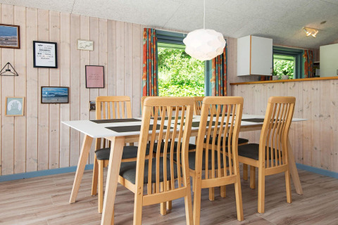 Eethoek met zes houten stoelen en tafel in een vakantiehuis in Børkop, Denemarken, lichte muren, wanddecoratie.