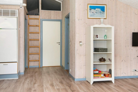 Interieur van een vakantiehuis in Børkop, Denemarken met boekenkast, ladder, deur en houten vloer.