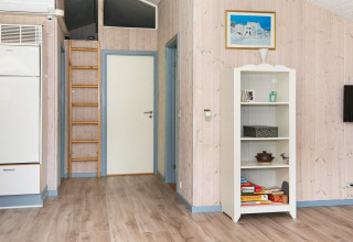 Interieur van een vakantiehuis in Børkop, Denemarken met boekenkast, ladder, deur en houten vloer.