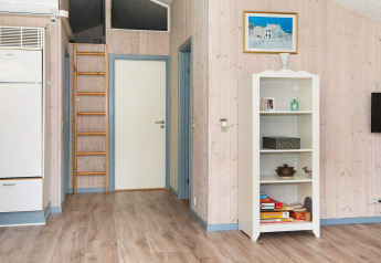 Vista interna di una casa vacanze a Børkop, Danimarca, con libreria, scala, porta e pavimento in legno.