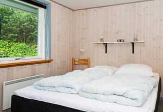 Slaapkamer met tweepersoonsbed, houten panelen, groot raam en plank in een vakantiehuis in Børkop.
