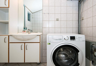 Wasseruimte met wasmachine en wastafel in een 6-persoons vakantiewoning in Børkop, Denemarken.