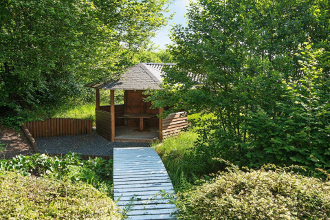 Houten prieel met overdekt terras en pad bij 6-persoons vakantiewoning in Børkop, Denemarken, omgeven door groen.