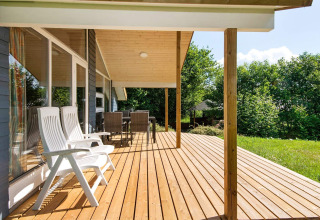 Zonnig houten terras met witte stoelen bij het 6-persoons vakantiehuis in Børkop, Denemarken.