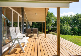 Træterrasse med havemøbler og udsigt til grøn have ved 6 personers feriehus i Børkop, Danmark.
