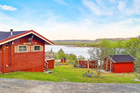 Rood chalet bij een meer met fietsen en bomen in Jarfjord, Zweden, zonnig weer en rustige sfeer.