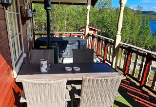 Veranda dello chalet '7 person holiday home in JARFJORD' con tavolo, sedie e vista sul lago.