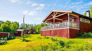 Chalet rojo en Jarfjord para 7 personas con gran porche, césped verde y cielo azul despejado.