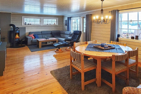 Woonkamer in chalet '7 person holiday home in JARFJORD' in Zweden met open haard, zetel en eettafel.