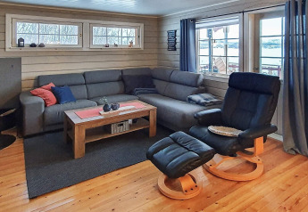 Gezellige woonkamer in een vakantiehuis in Jarfjord, Zweden, met grijze bank, stoel en buitenzicht.