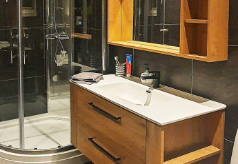 Moderne badkamer met houten kast, spiegel, douche en wastafel in vakantiechalet te Jarfjord, Zweden.