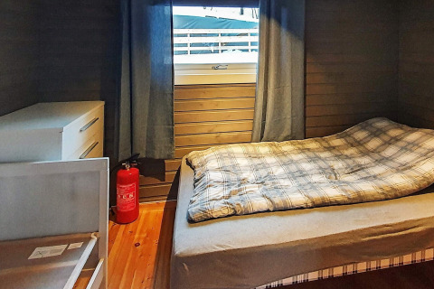 Slaapkamer chalet met eenpersoonsbed, kast, brandblusser en raam in 7-persoons vakantiehuis te Jarfjord, Zweden.