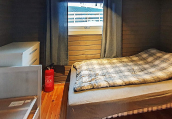 Bedroom in a chalet with a single bed, dresser, fire extinguisher, and window at 7 person holiday home in Jarfjord, Sweden.