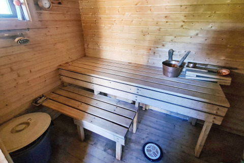 Interno di una sauna tradizionale con panche di legno e secchi in uno chalet per 7 persone a Jarfjord, Svezia.